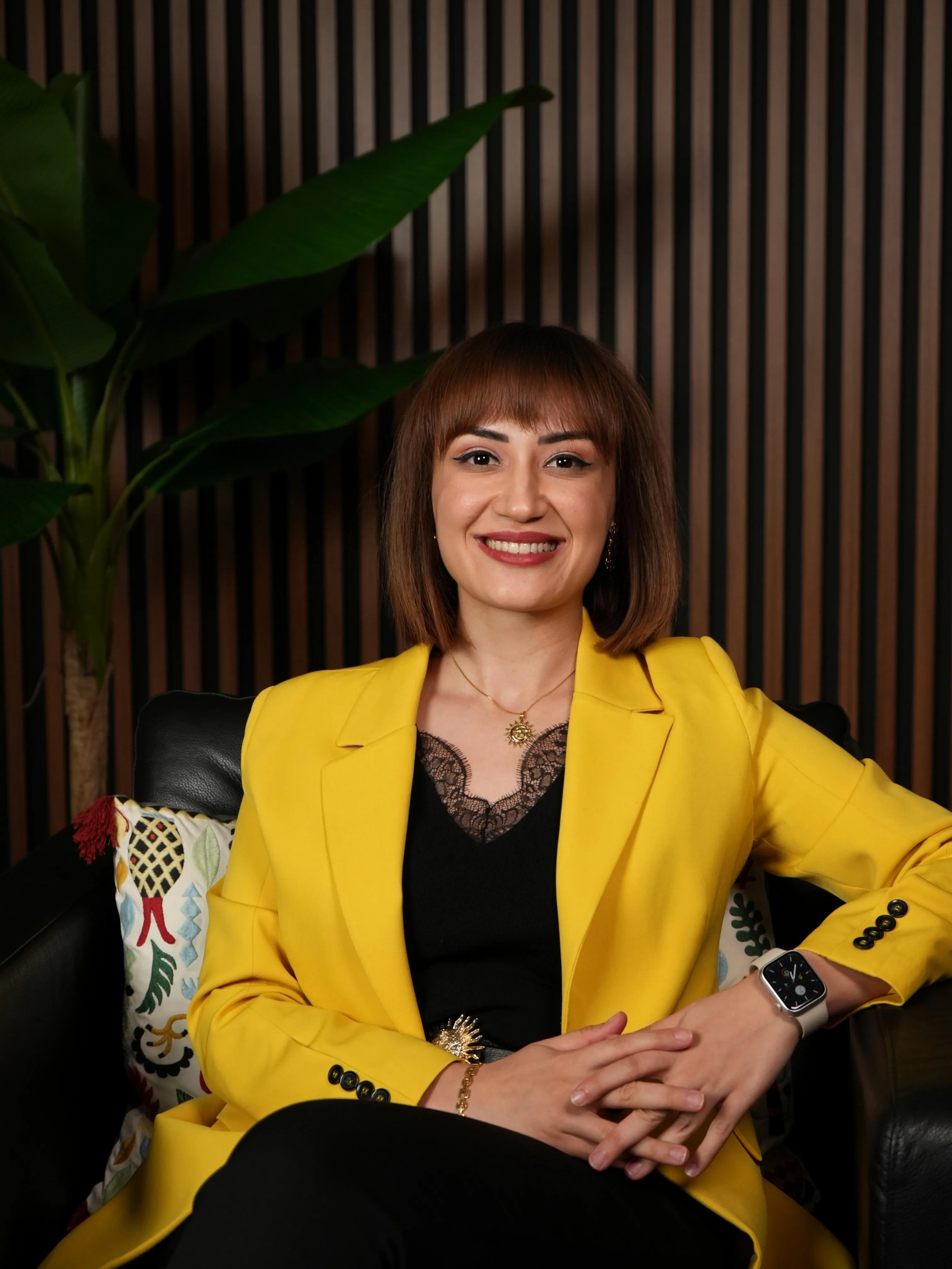 Fzt. İlknur Cansu Koplay, sarı ceketiyle koltukta oturuyor.
